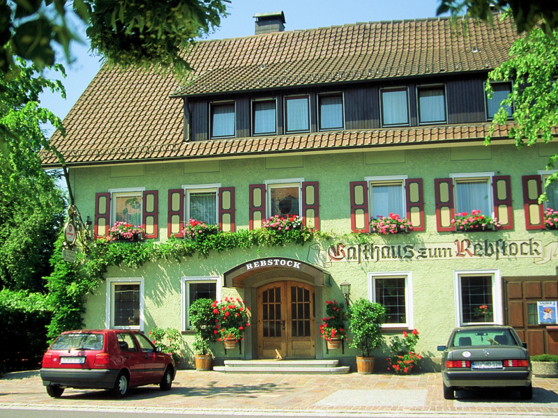 Das Gasthaus von vorne mit den Parkplätzen im Vordergrund